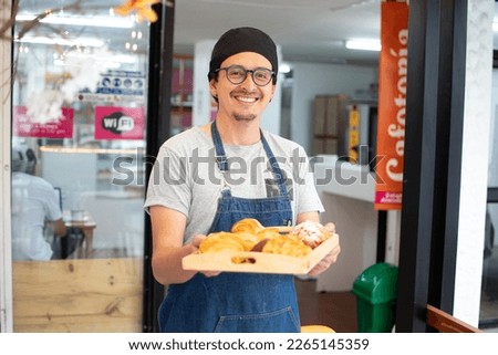 Baker showing the croissants on the tray. Happy baker showing the different croissants. Royalty-Free Stock Photo #2265145359