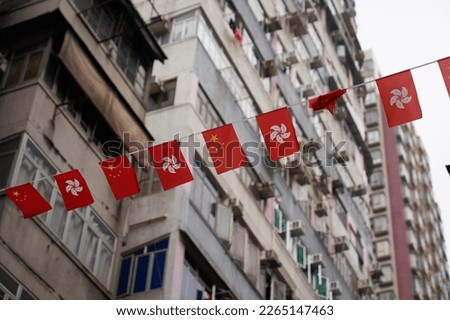                                A row of Chinese and Hong Kong flags hang over an urban street in central Hong Kong with apartment buildings in the background.