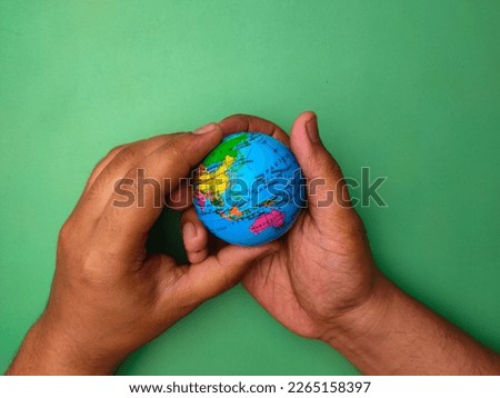 Hand holding earth globe on a green background.Nature and earth concept.