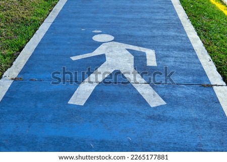 Sidewalk painted with a pedestrian sign, on a blue background.