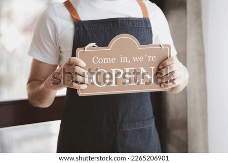Man holding open and close sign in front of entrance, Goods and Service shop clerk holding sign to notify customers whether the store is open or closed, the opening of the restaurant.