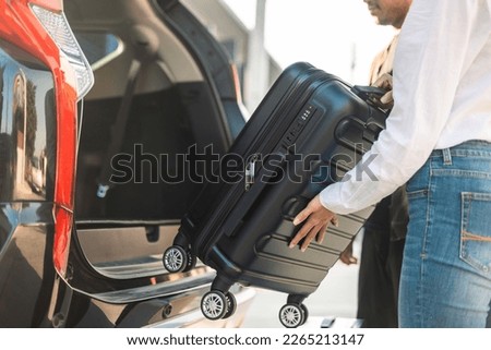 Happy couple puts his suitcase in the back of the car and prepares to leave for honeymoon trip. Husband and wife open the back of the car put luggage travel. Couple moving into new home at moving day Royalty-Free Stock Photo #2265213147