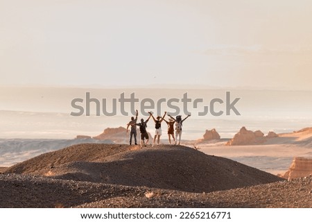 Group of happy tourists stands with open arms at desert view point Royalty-Free Stock Photo #2265216771