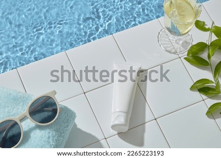 Summer vacation background concept with sunglasses, towel, glass of cool water and green leaves. Space for cosmetic product mockup. Product and promotion concept for advertising