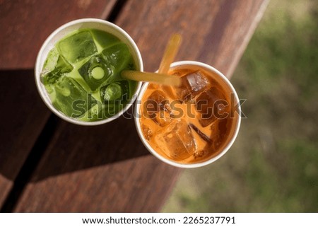Ice green and red Thai tea in eco-friendly paper glass with a rice straws. Solving problem of using plastic in Thailand Local beverage product of Thailand Asia Outdoor Drinking on open air