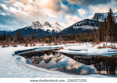 Beautiful view of Three Sisters Mountains with snow covered on bow river reflection in the morning on winter at Canmore, Alberta, Canada Royalty-Free Stock Photo #2265271355