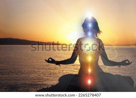 woman in yoga pose on beach sunset view, glowing seven all chakra. Kundalini energy. girl practicing meditation outdoors. Silhouette. Royalty-Free Stock Photo #2265278407
