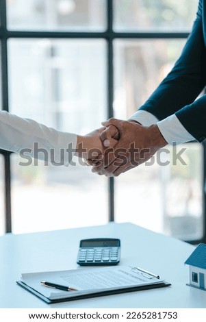 Shaking hands after agreeing to sign a contract, realtor suggestion a new house model assisting client to sign contract agreement with insurance to happy living, concerning mortgage loan offer
