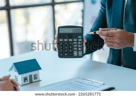 offer mortgage loans calculate numbers on calculator, realtor suggestion a new house model assisting client to sign contract agreement with insurance to happy living, concerning mortgage loan offer