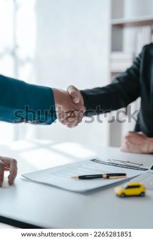Shaking hands after succesful sign a contract and pay for money, A car dealer or sales manager offers to sell a car and explains the terms of signing a car and insurance contract.