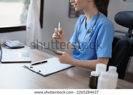 Portrait of a female doctor using a tablet computer and a document analyzing a patient's condition before treating
