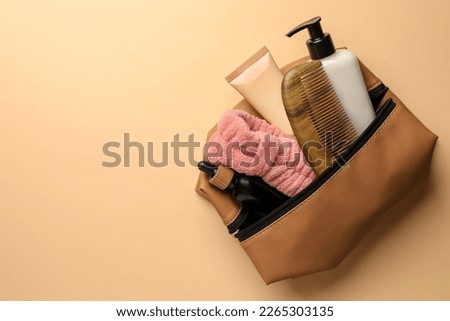 Preparation for spa. Compact toiletry bag with different cosmetic products on beige background, top view. Space for text Royalty-Free Stock Photo #2265303135