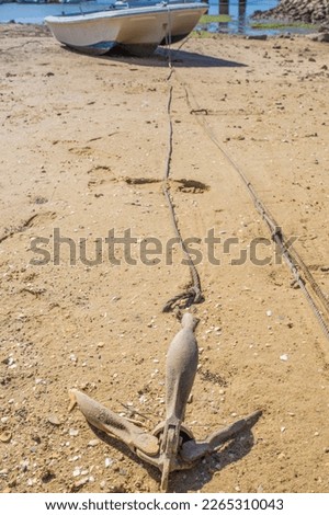 Anchor from fishing boat docked in low tide sand. Cabanas de Tavira, Portugal