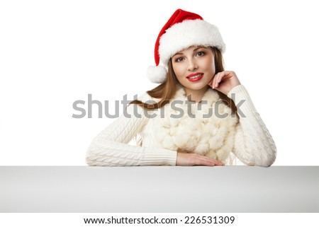 Beautiful christmas woman in santa hat pointing empty board, isolated on white background