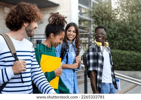 College friends walk to class together. Multiracial university students in campus talk and have fun outdoors. Royalty-Free Stock Photo #2265333781