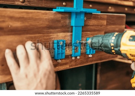 carpenter use a cabinet hardware jig adjustable punch locator drill guide sleeve for Install cabinet handles and knobs ,DIY maker and woodworking concept. selective focus Royalty-Free Stock Photo #2265335589