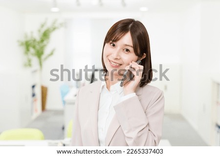 Young Japanese woman in office attire talking on phone