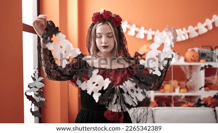 Young blonde woman wearing katrina costume decorating halloween party at home