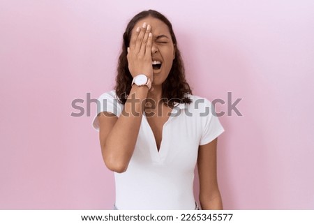 Young hispanic woman wearing casual white t shirt yawning tired covering half face, eye and mouth with hand. face hurts in pain. 
