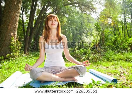 Young girl doing yoga lotus pose in the park
