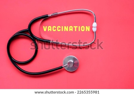 Stethoscope isolated on red background with word "vaccination". Selective focus