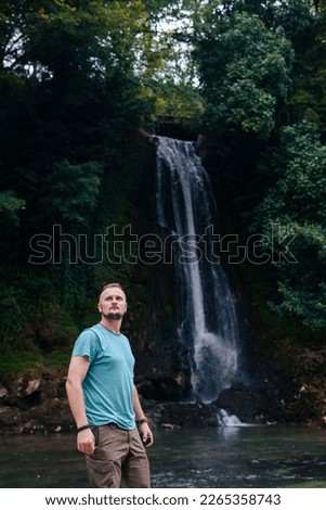 A man, a tourist, a traveler enjoys the wonderful nature. Stones in a mountain river. Vertical photo. Vacation and tourism. Abhesi waterfall.