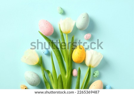 Happy Easter card. Bouquet of tulips and Easter eggs on light blue background. Flat lay, top view