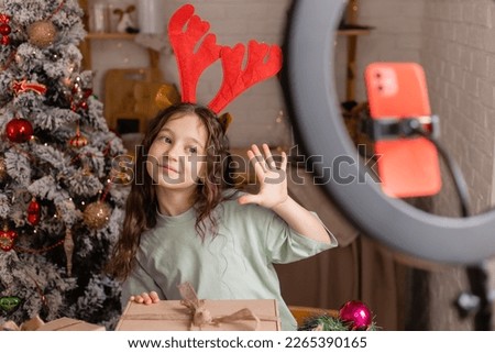 girl in reindeer horns conducts a Christmas live broadcast for social networks via a smartphone. High quality photo