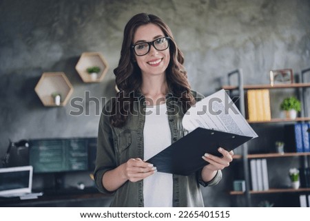 Photo of confident smiling lady secretary wear eyeglasses reading contract indoors workplace workstation
