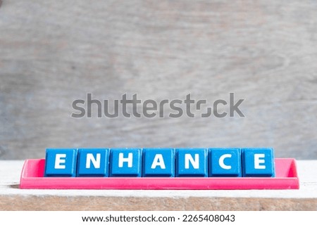 Tile alphabet letter with word enhance in red color rack on wood background