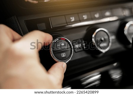 Closeup of hand adjusting the conditioner in a modern car. Dashboard with air flow, climate control and temperature button temperature button inside transport. Car HVAC System. Detail interior of car. Royalty-Free Stock Photo #2265420899