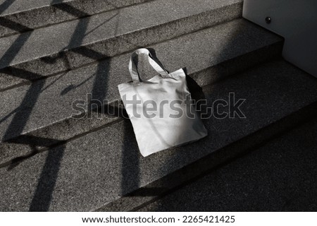 Tote bag mockup template on a concrete ladder with deep sunlit shadows. Isolated surface to place your design.  Royalty-Free Stock Photo #2265421425