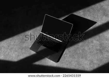 Laptop mockup template on a concrete background with deep shadows, real photo. Blank isolated to place your design.	