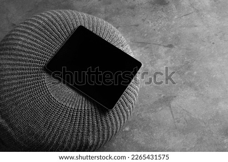 Tablet computer mockup template on a fabric round poof, concrete background with deep shadows, real photo. Blank isolated to place your design.	
