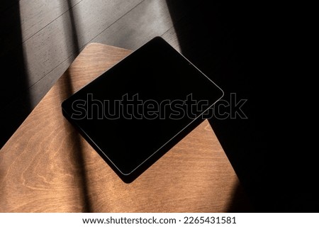 Tablet computer mockup template on wooden table with deep shadows, real photo. Blank isolated to place your design.	