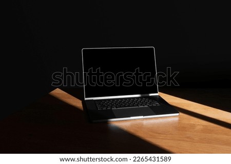 Laptop mockup template on wooden table with deep shadows, real photo. Blank isolated to place your design.	