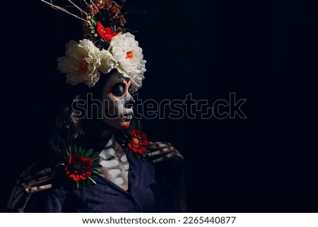 Woman with mexican skull halloween makeup on dark background. Day of the dead aka Dia de los Muertos and halloween concept. Royalty-Free Stock Photo #2265440877