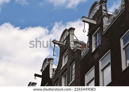 Typical Amsterdam house with big pulley hook near the roof to carry the furniture while moving. A part of the building against blue sky, close up. Royalty-Free Stock Photo #2265449083