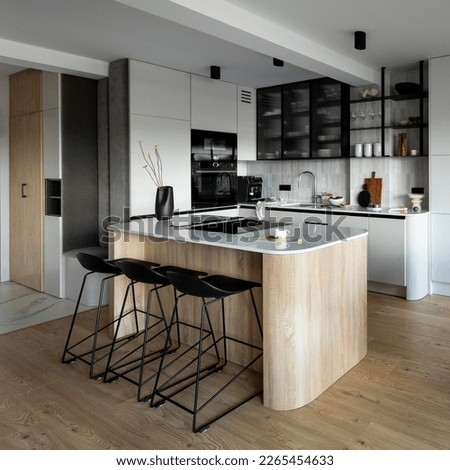 Modern composition of kitchen space with design kitchen island, black hookers, grey table, flowers, furnitures, big window and elegant personal accessories. Stylish home decor. Template
