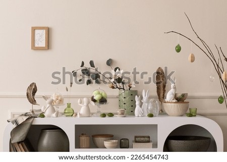 Interior design of easter living room interior stylish sideboard, colorful easter eggs, easter bunny sculpture, vase with leaves, magnolia and personal accessories Home decor. Template. Royalty-Free Stock Photo #2265454743