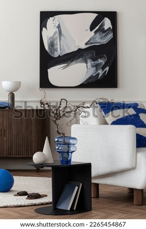 Aesthetics composition of living room interior with mock up poster frame, white armchair, vase with branch, black coffee table, geometric sculptures and personal accessories. Home decor. Template.
