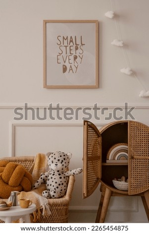 Cozy kids room interior with mock up poster frame, plush toys, orange pillow, braided armchair, rattan sideboard, clouds garland, beige wall with stucco and personal accessories. Home decor. Template.