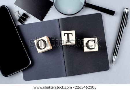 Word OTC stands for Over-the-counter on a wooden block on black notebook with smartpone, credit card and magnifier Royalty-Free Stock Photo #2265462305
