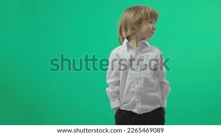 Little blonde hair child standing and holding his hands in his trouser pockets