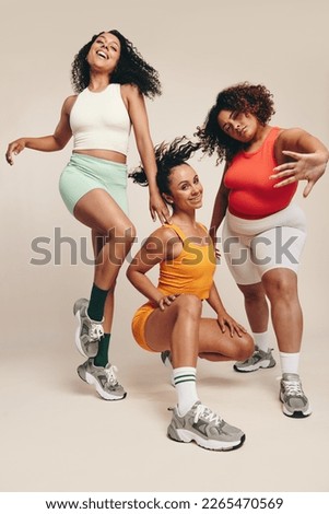 Fit young women strike confident poses and looking at the camera, dressed in vibrant sports clothing. Group of females embodying a passion for sport, fitness and an active lifestyle in a studio. Royalty-Free Stock Photo #2265470569