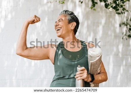 Happy elderly woman celebrating her fitness achievement after a great outdoor workout session, flaunting her strong bicep. Fit senior woman expressing her pride in her successful exercise routine. Royalty-Free Stock Photo #2265474709