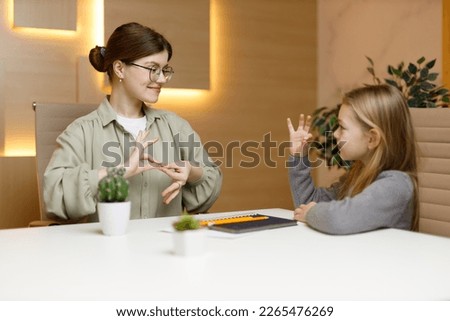 A volunteer communicates in sign language with a deaf girl. Specialized education for disabled children. Royalty-Free Stock Photo #2265476269