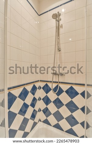 a bathroom with blue and white tiles on the walls, shower head in the corner to the wall is tiled