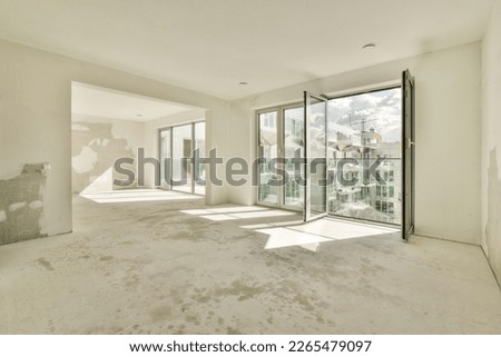 an empty living room with large windows and no one person in the photo is visible on the wall to the right Royalty-Free Stock Photo #2265479097