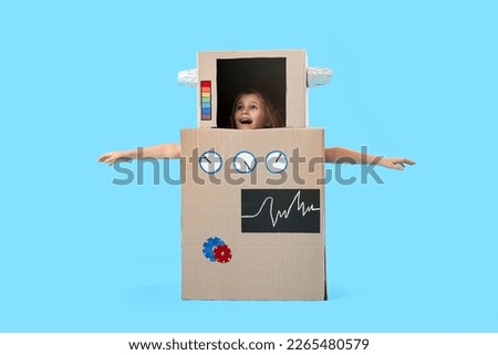 Little girl in cardboard robot costume on blue background